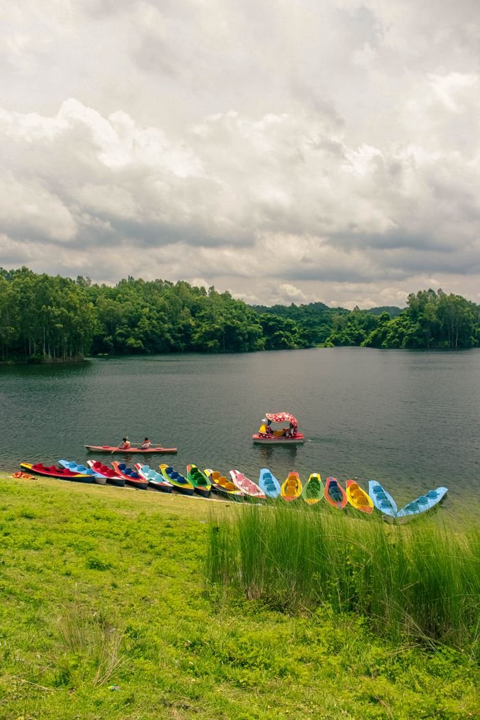 Vibrant canoes on a serene lake in rural Bangladesh, surrounded by lush greenery.