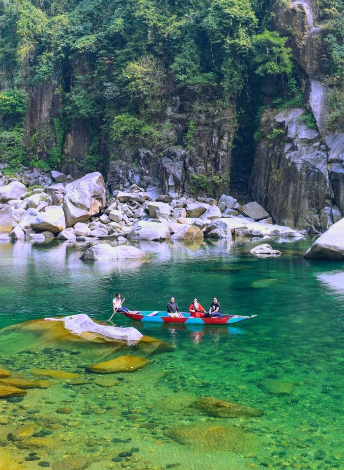services-03 A group of people canoeing in a clear green lake surrounded by rocky cliffs and lush greenery.