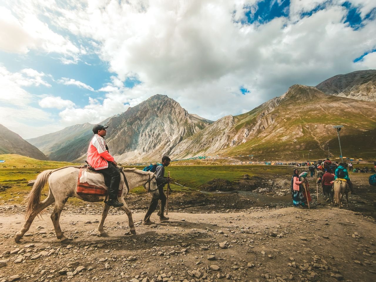 Travelers ride horses through a mountainous landscape, capturing an adventurous journey.