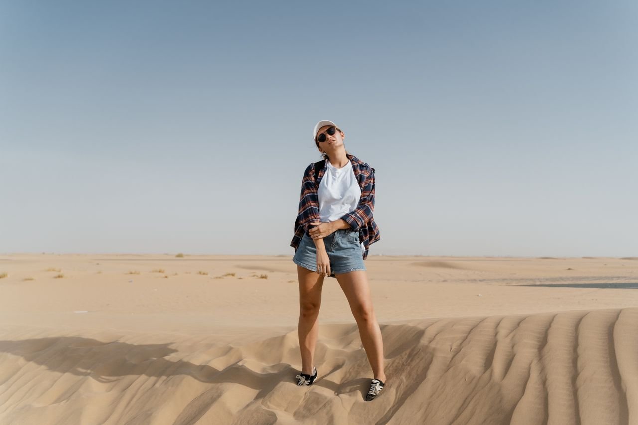 hero-img Woman posing in the desert with a casual outfit and clear sky background.